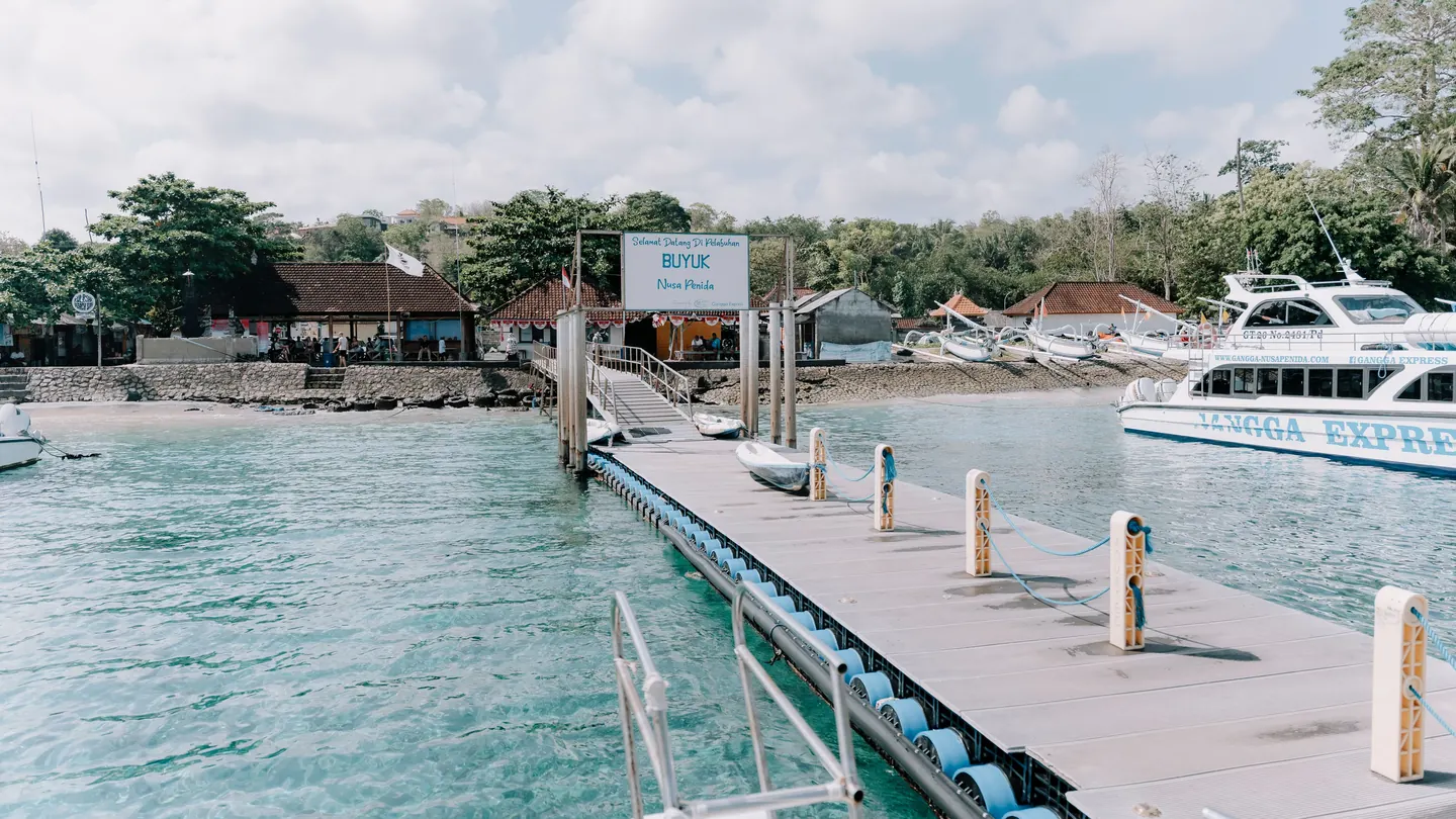 A pier with boats moored in clear water at a harbour on Nusa Penida