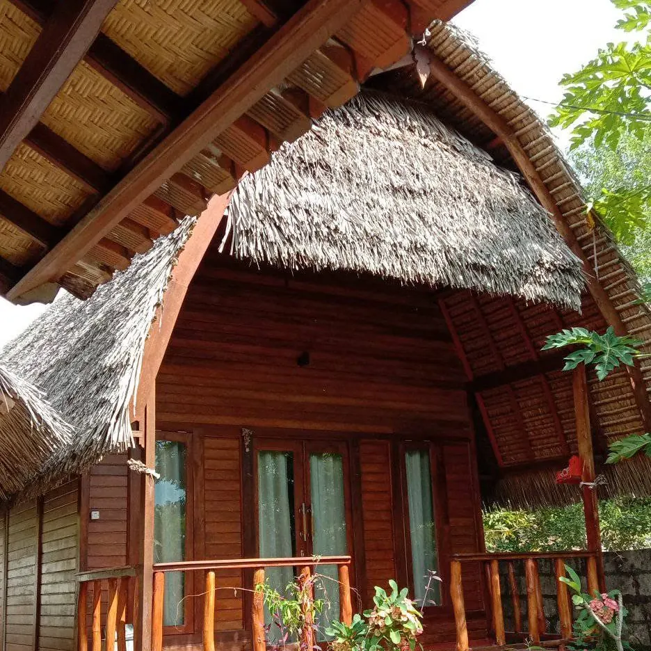 Timber cabin with a high thatched roof and a veranda