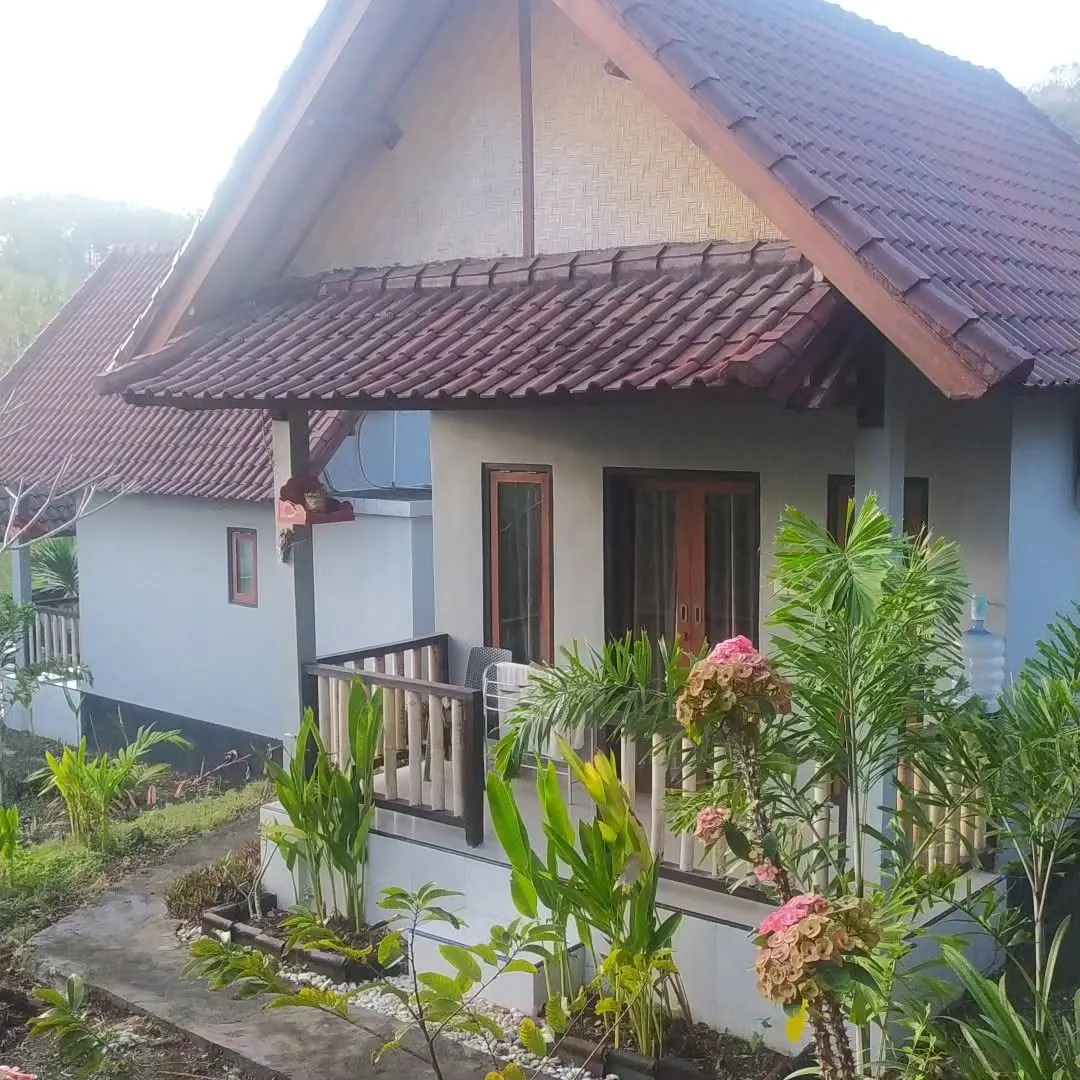 White bungalow with a brown tiled gable and flowering plants in front